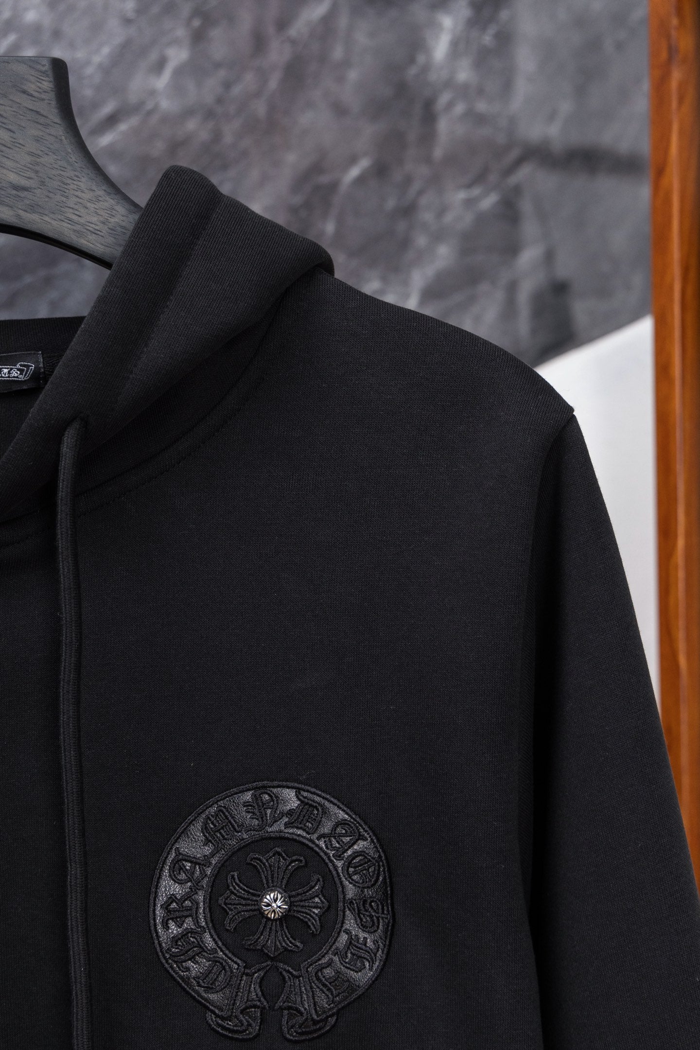 Black long zip hoodie side view with circular embroidered emblem on chest