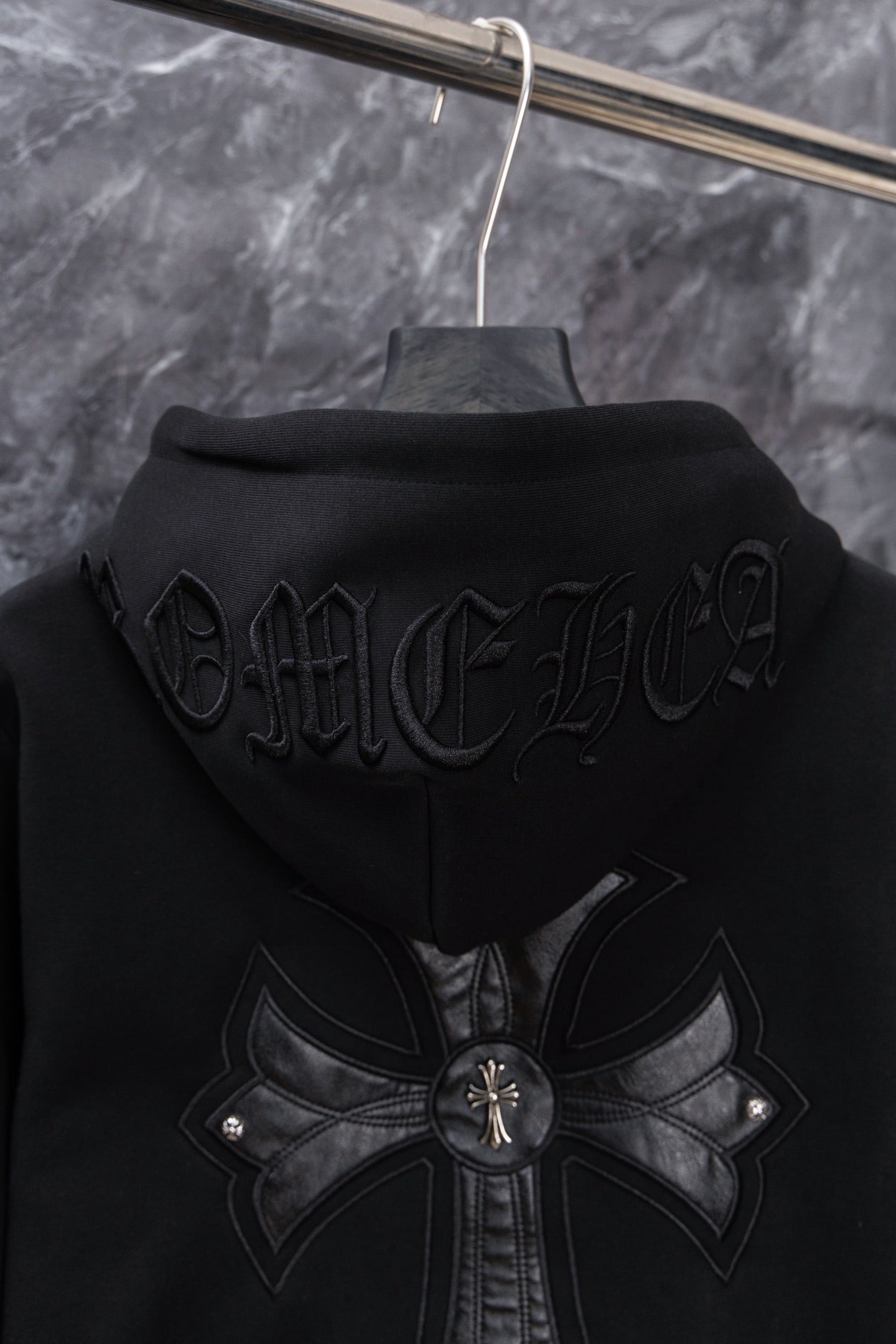 Black long zip hoodie front view with back-style cross emblem and hood detail