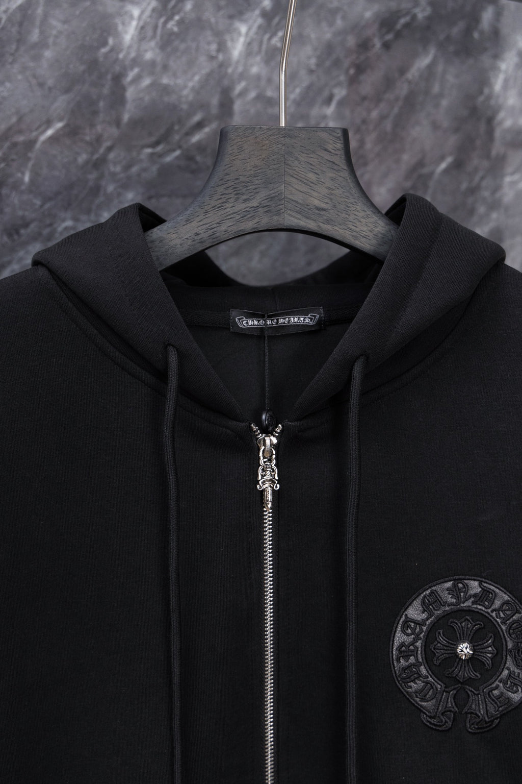Black long zip hoodie with hood and metal zipper pull, circular chest emblem