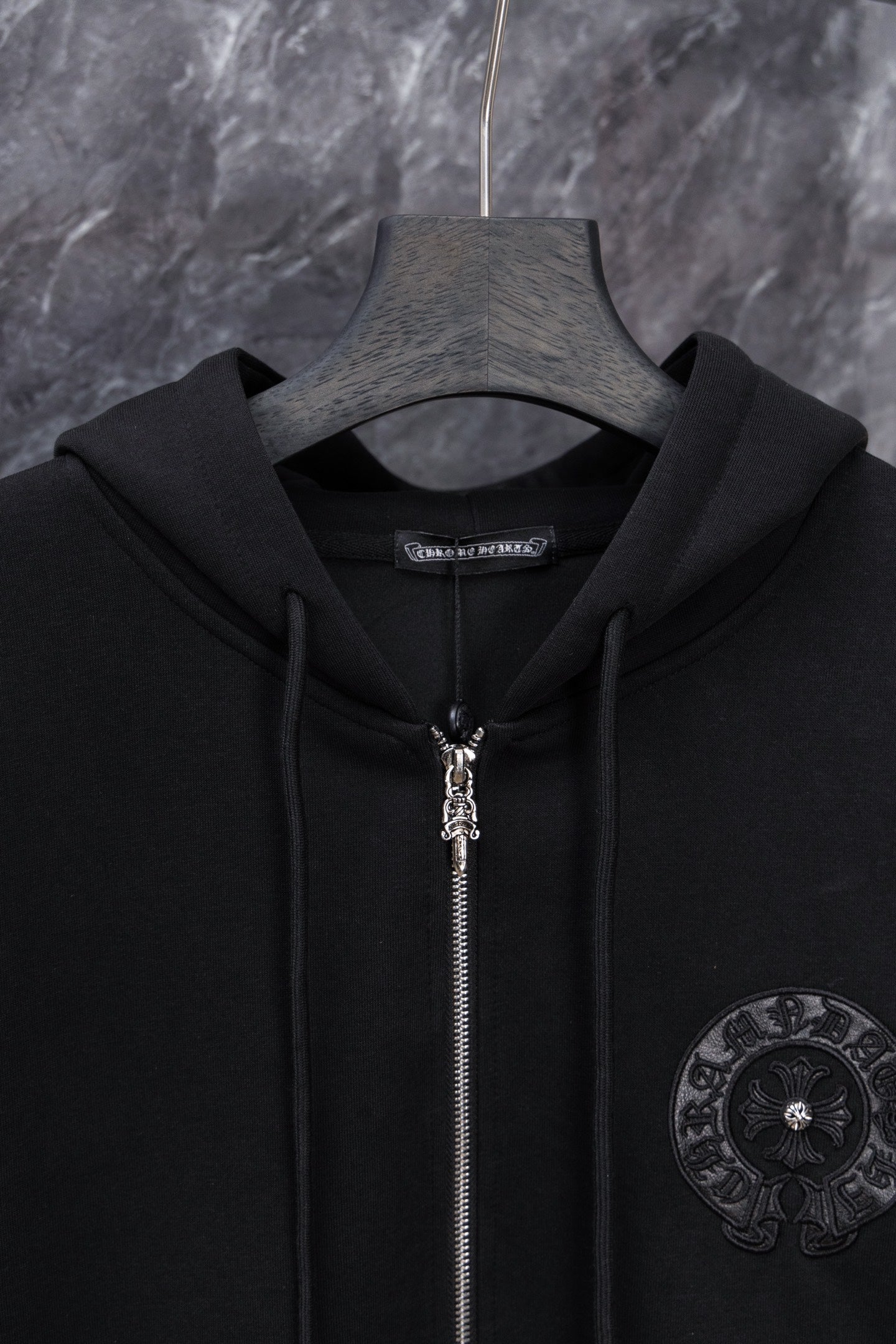Black long zip hoodie with hood and metal zipper pull, circular chest emblem