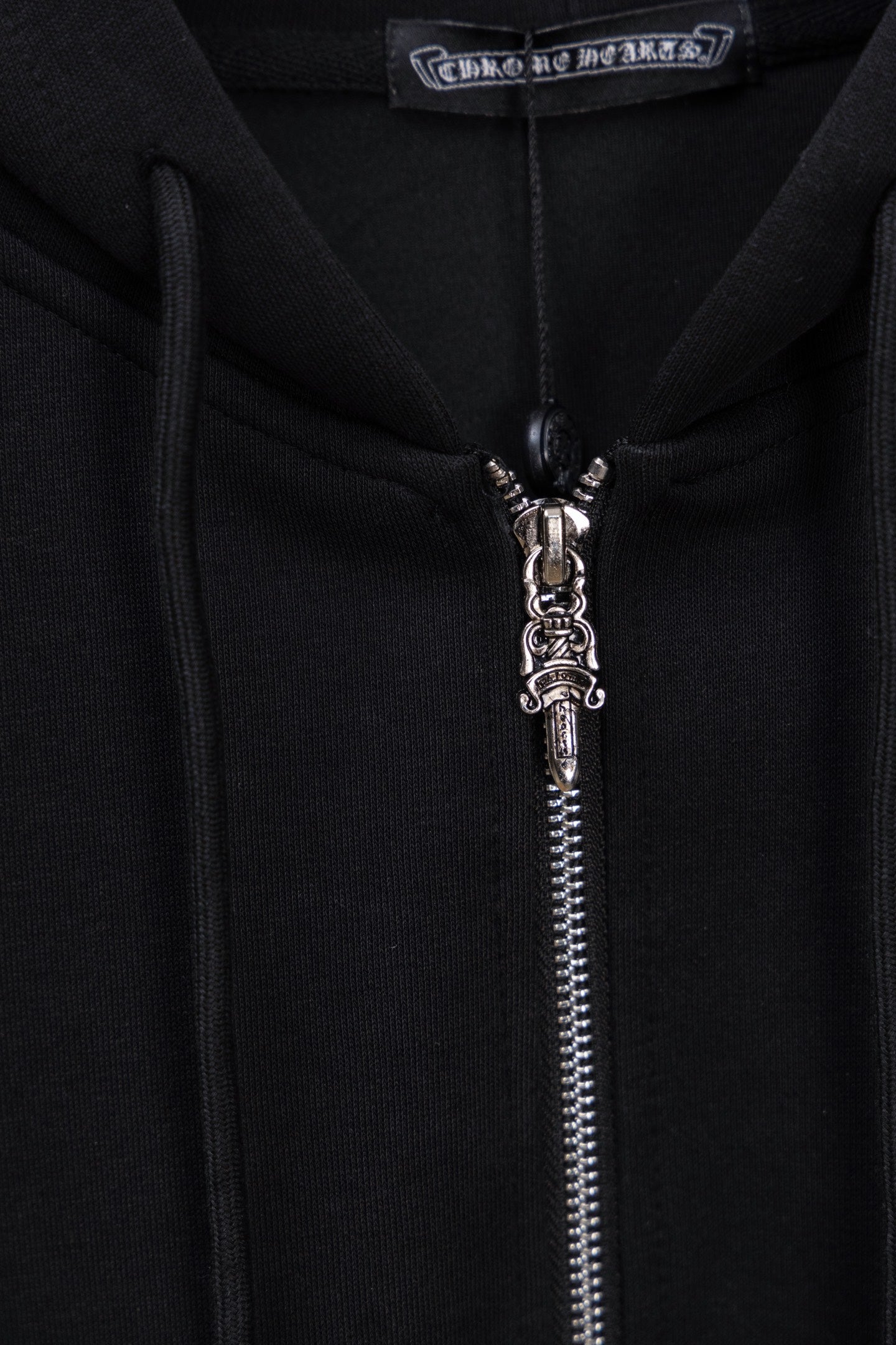 Black hoodie zipper with metal pull and small cross charm