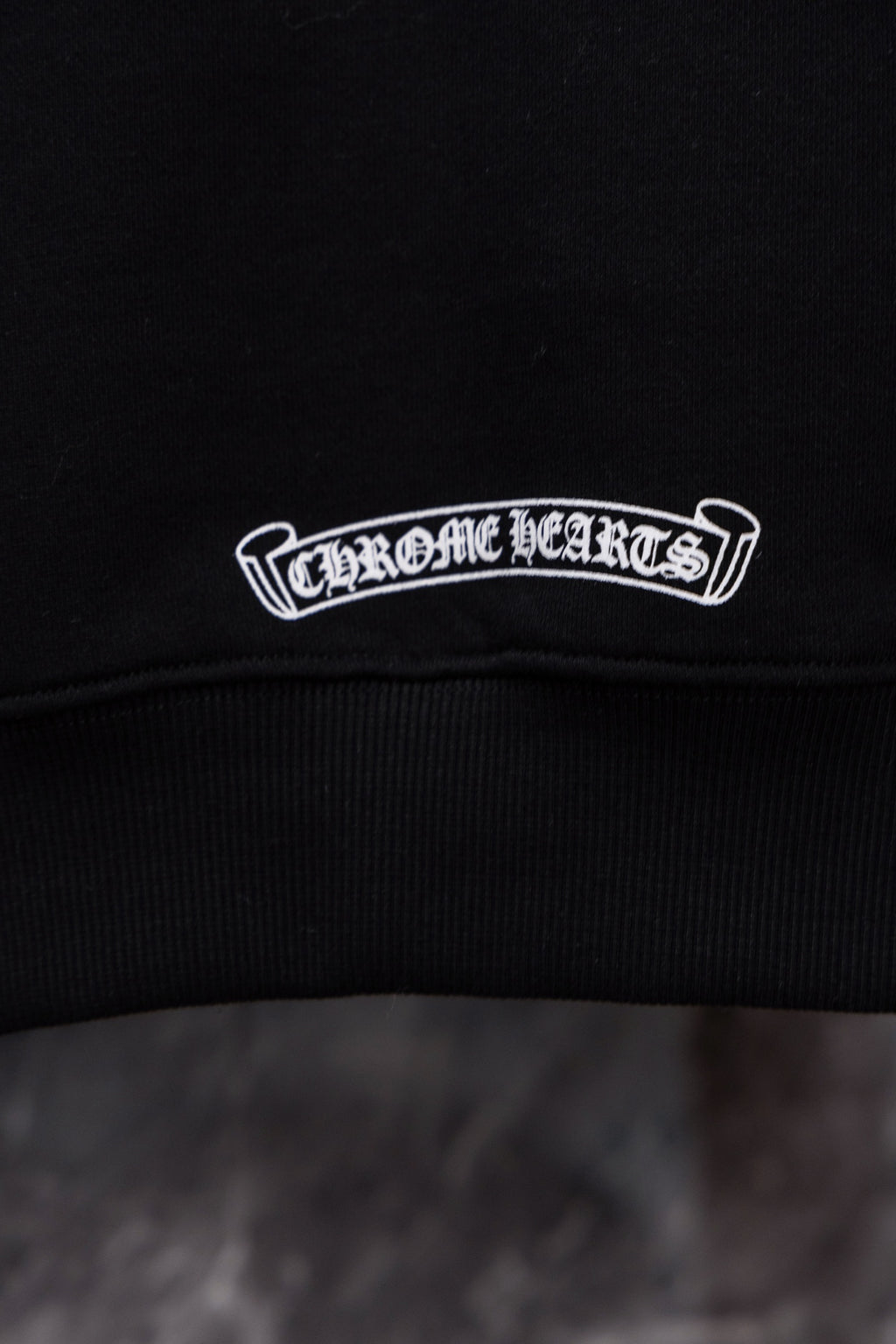 Black hoodie neckline with embroidered logo patch in white