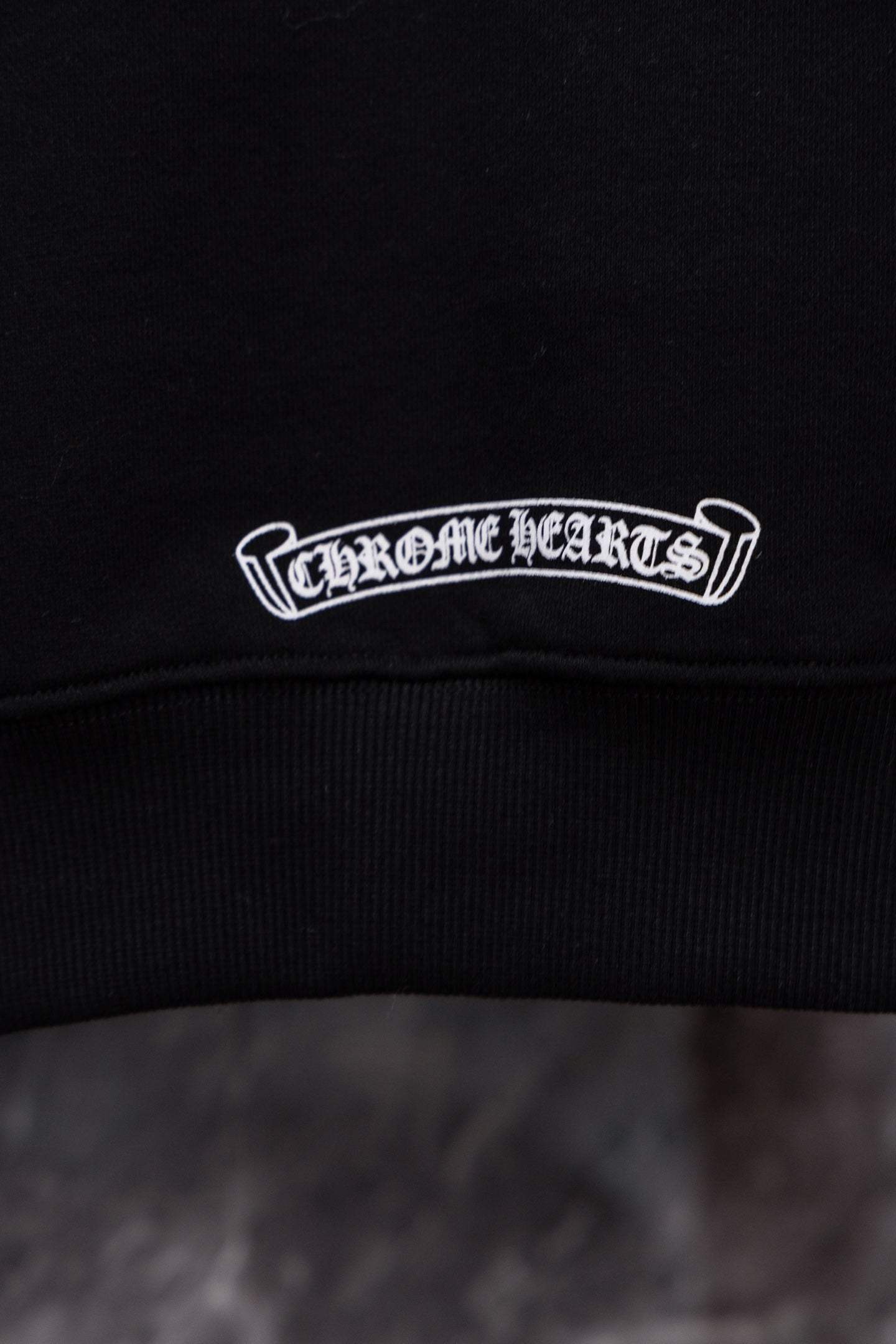 Black hoodie neckline with embroidered logo patch in white