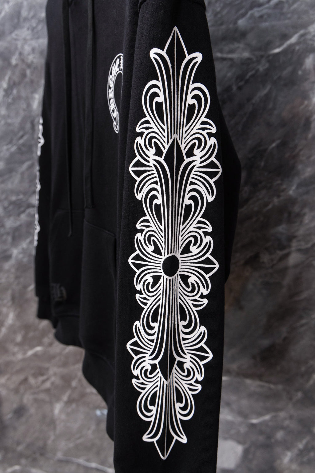 Black hoodie sleeve with large white ornamental graphic