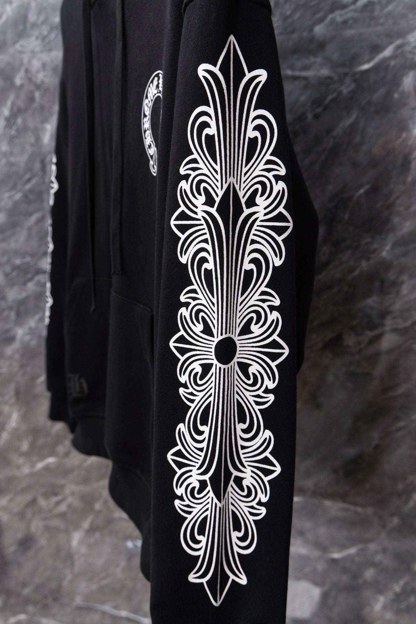 Black hoodie sleeve with large white ornamental graphic