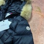 Navy puffer coat with green faux-fur cuffs, front zipper and logo patch