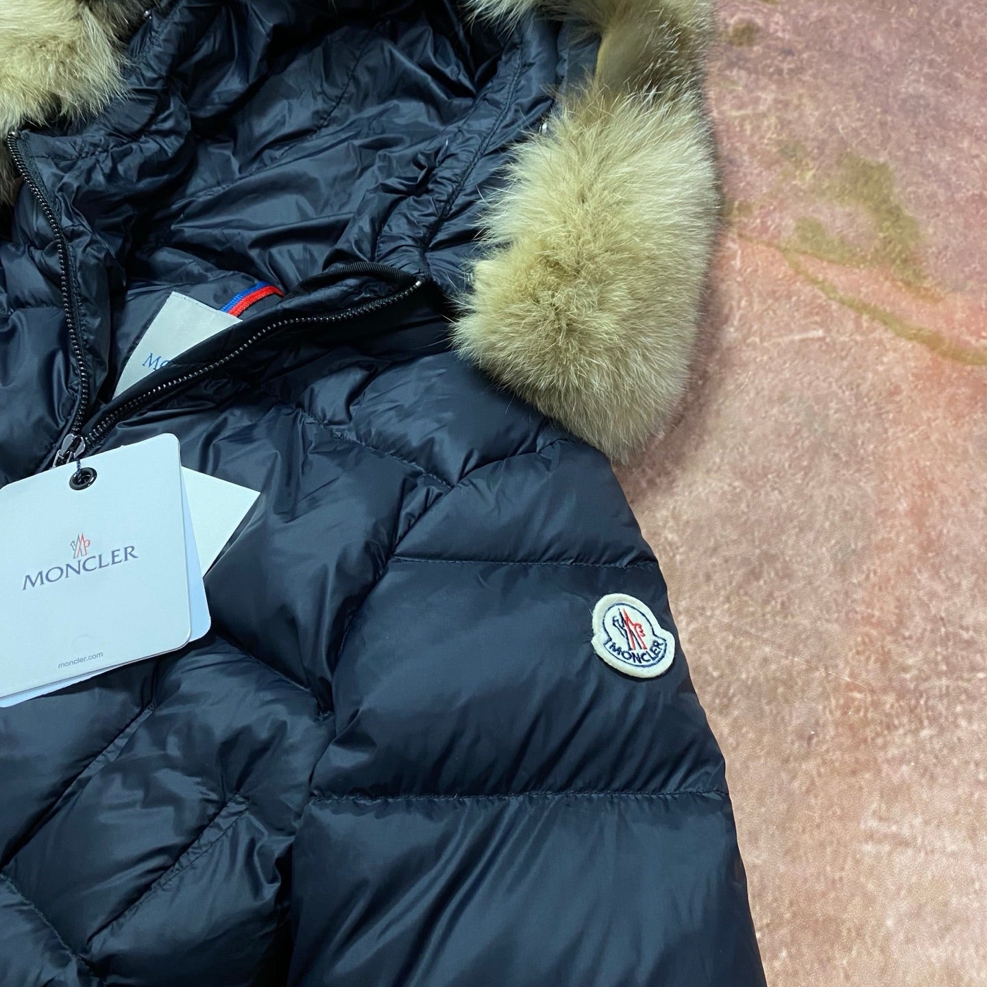 Navy puffer coat with green faux-fur cuffs, front zipper and logo patch