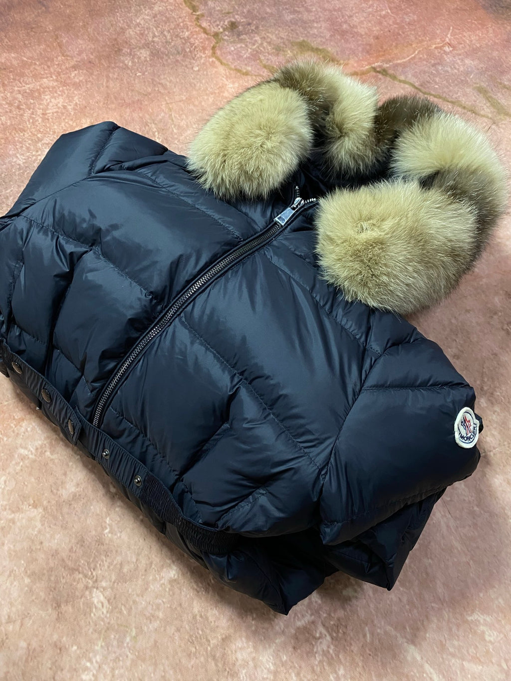 Long navy puffer coat with green faux-fur hood trim and front zipper closure