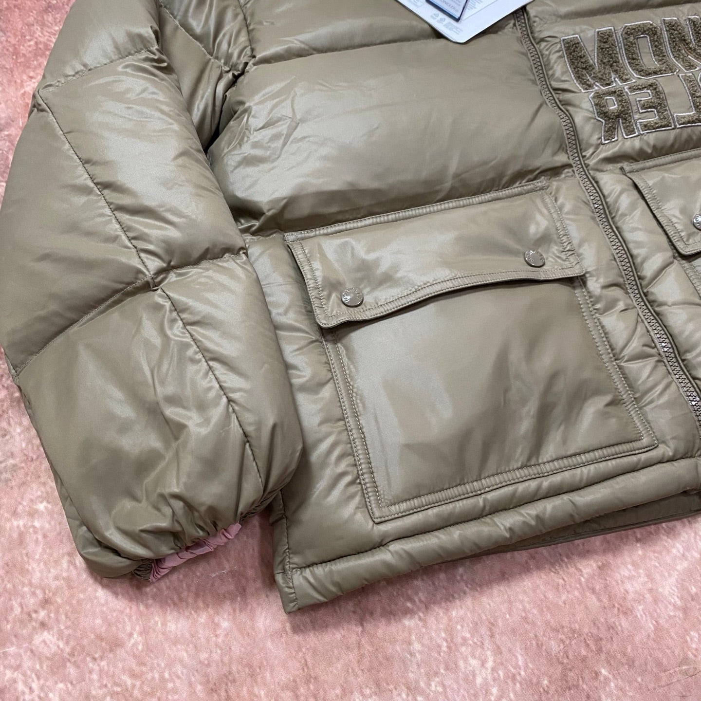 Olive green puffer jacket with flap chest pocket, quilted fabric and snap buttons.