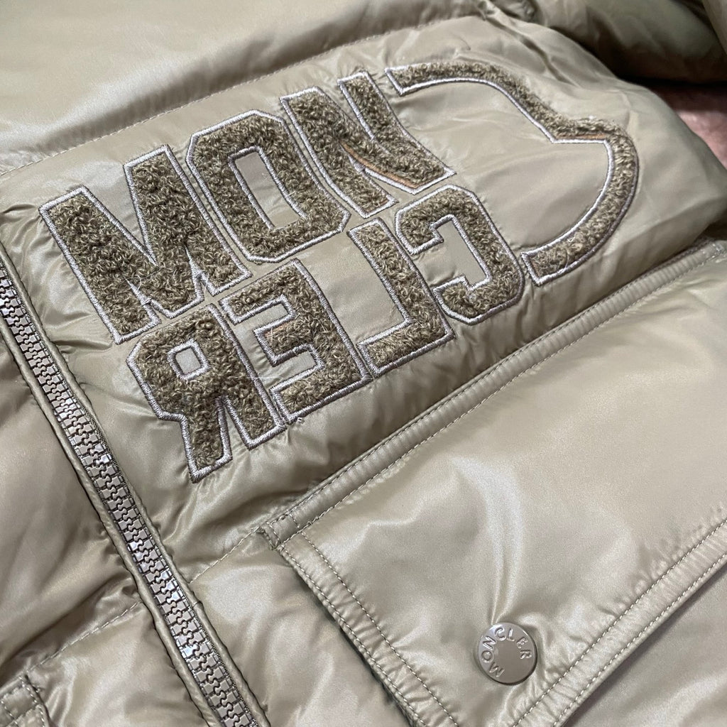 Olive green puffer jacket with raised metallic logo lettering on chest panel.