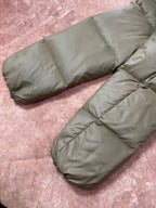 Olive green long puffer jacket sleeves and hem, padded quilted construction on display.