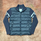Long puffer jacket with dark blue quilted body, knit sleeves, and front zipper