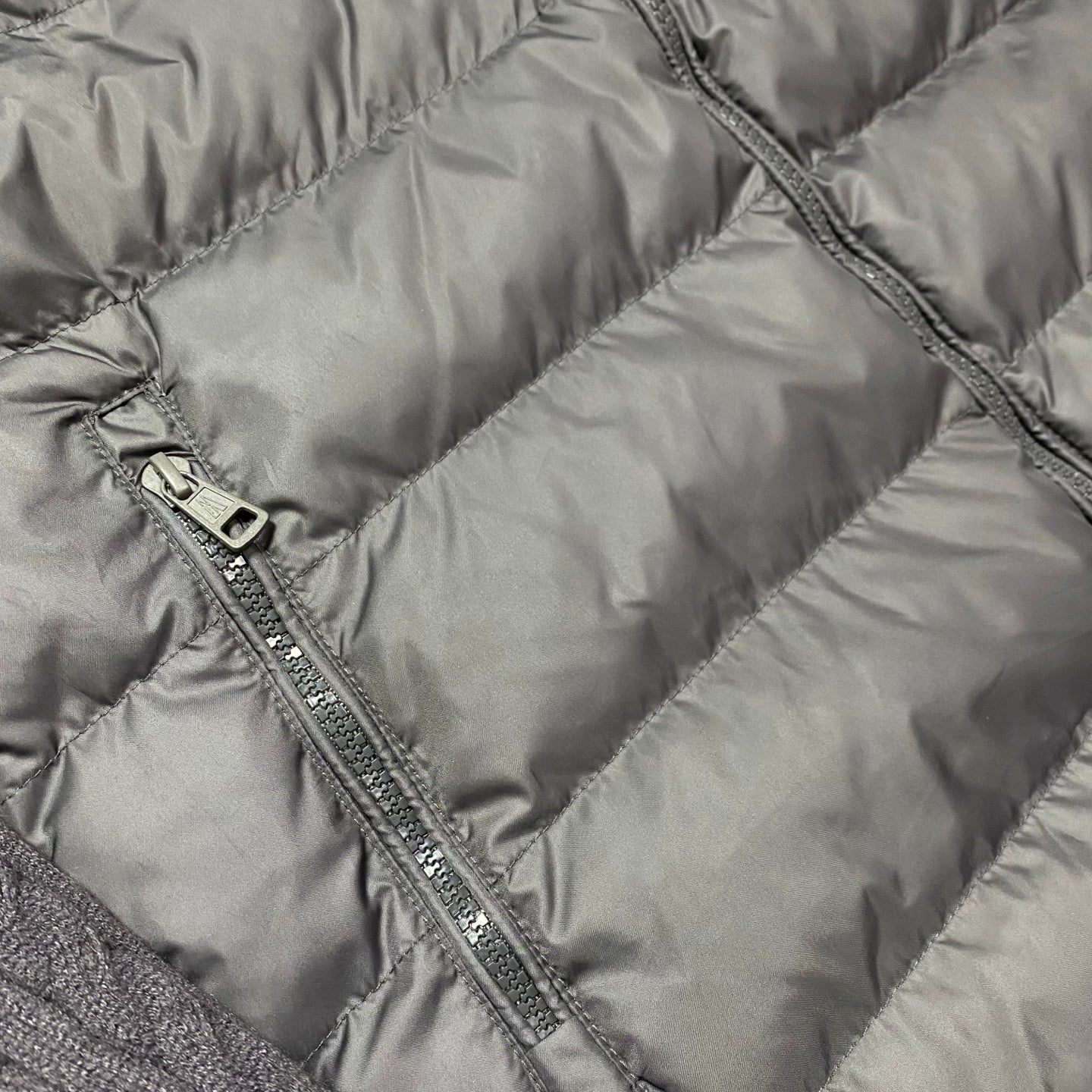 Quilted puffer jacket panel close-up with metal zipper and stitched channels