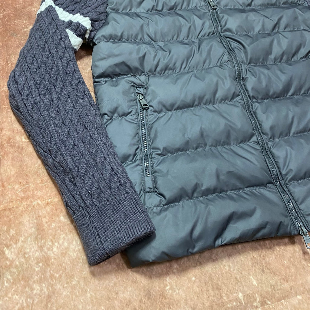 Long puffer jacket close-up with quilted padding, front zipper, and knit sleeve