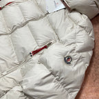 Moncler cream puffer jacket chest area with logo patch and red zipper pull