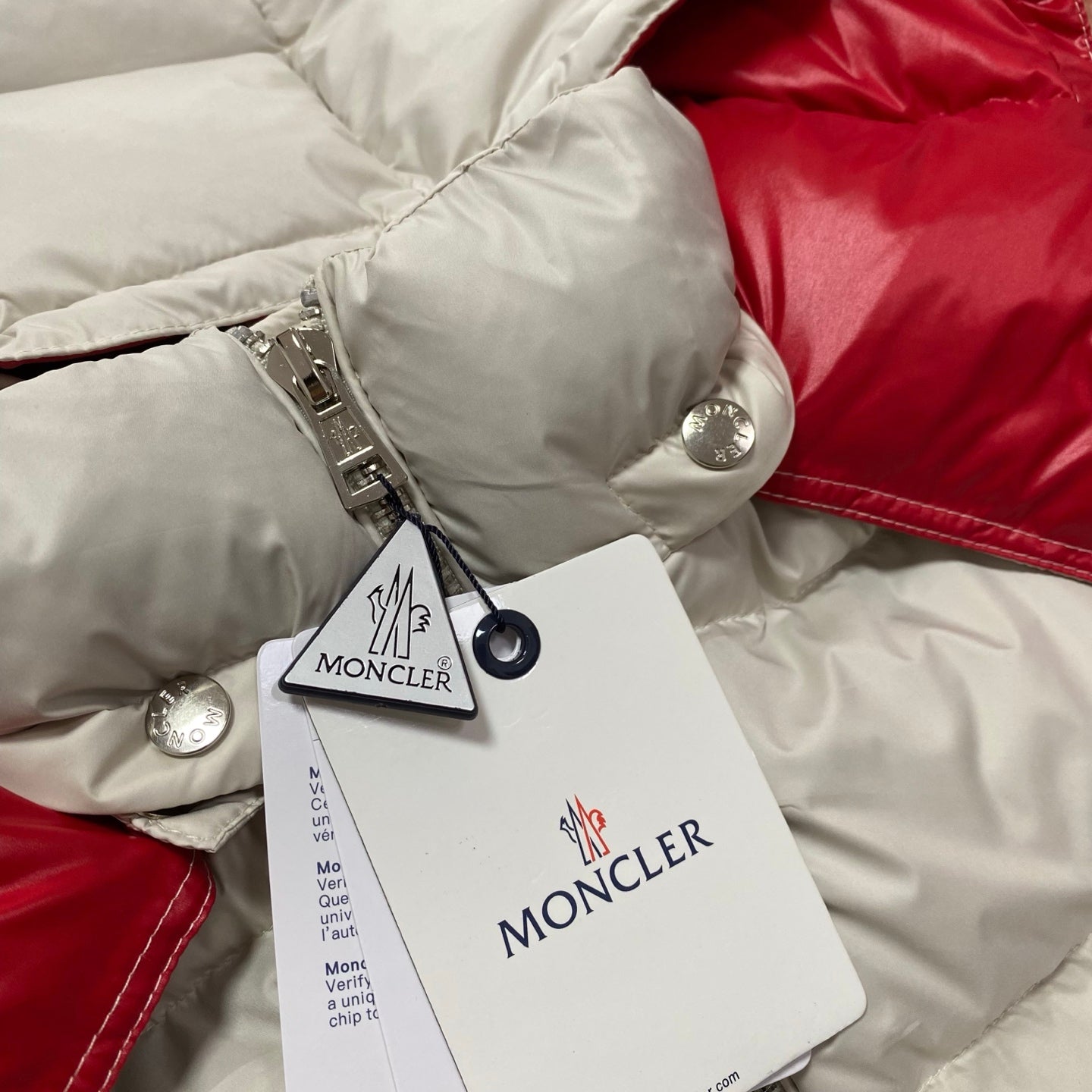 Moncler cream puffer jacket cuff with snap buttons and hang tags near the sleeve