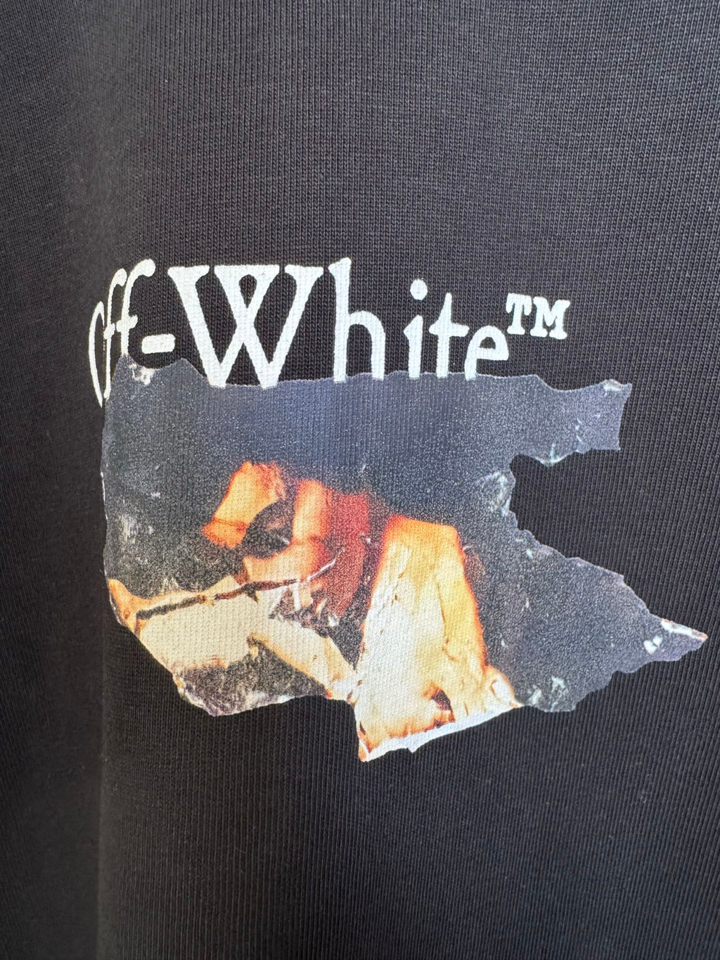 Black T-shirt graphic close-up with white Off-White text and torn print
