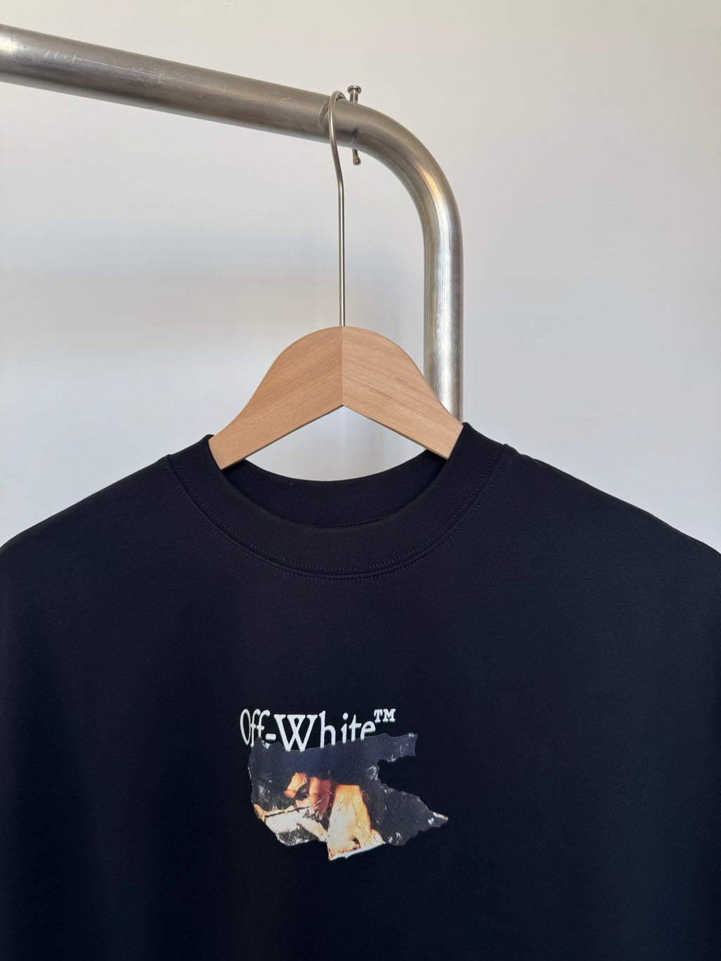 Black T-shirt on a hanger with crew neck and Off-White logo graphic
