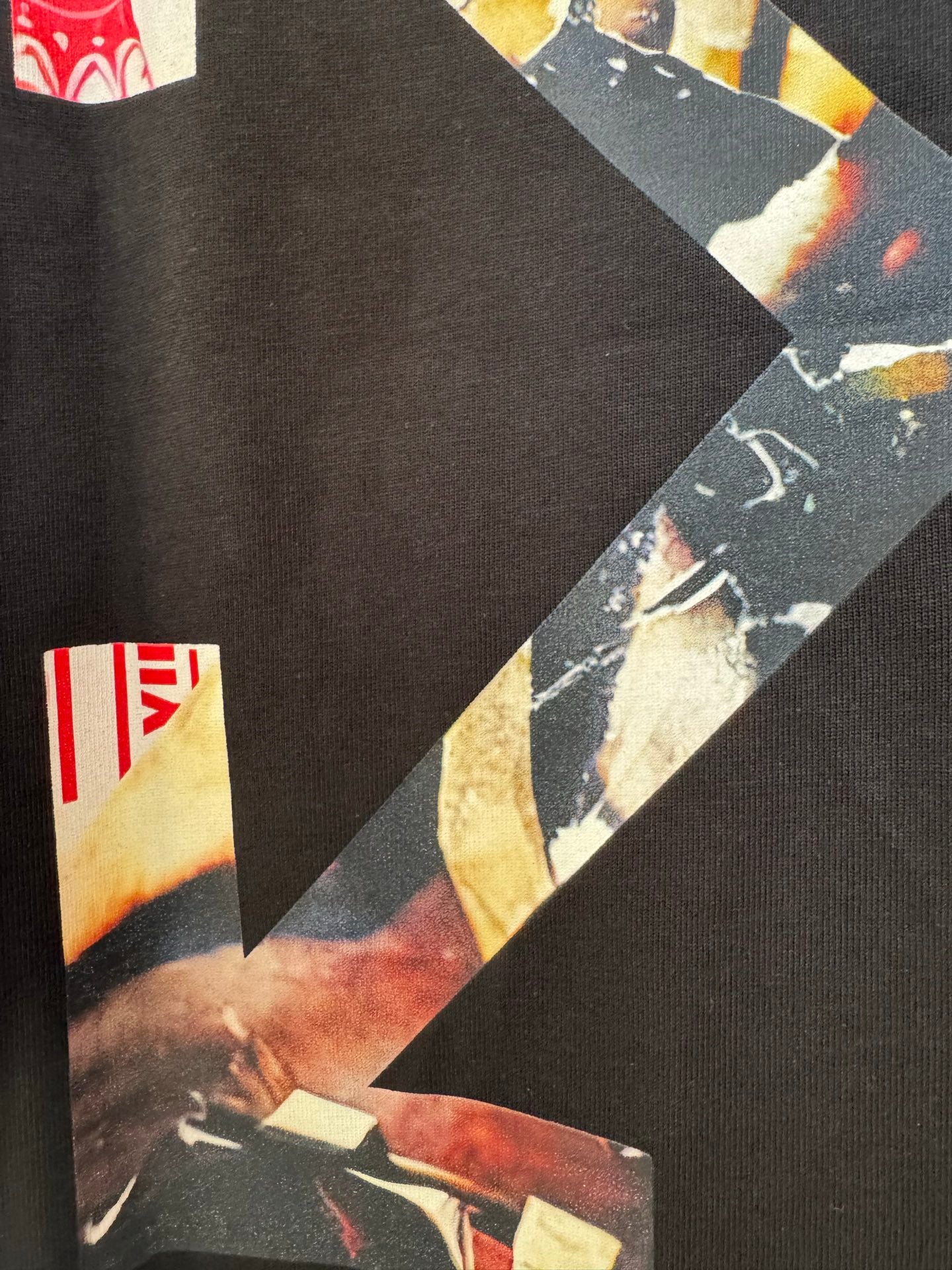 Black T-shirt close-up of X-shaped graphic with red and off-white label details