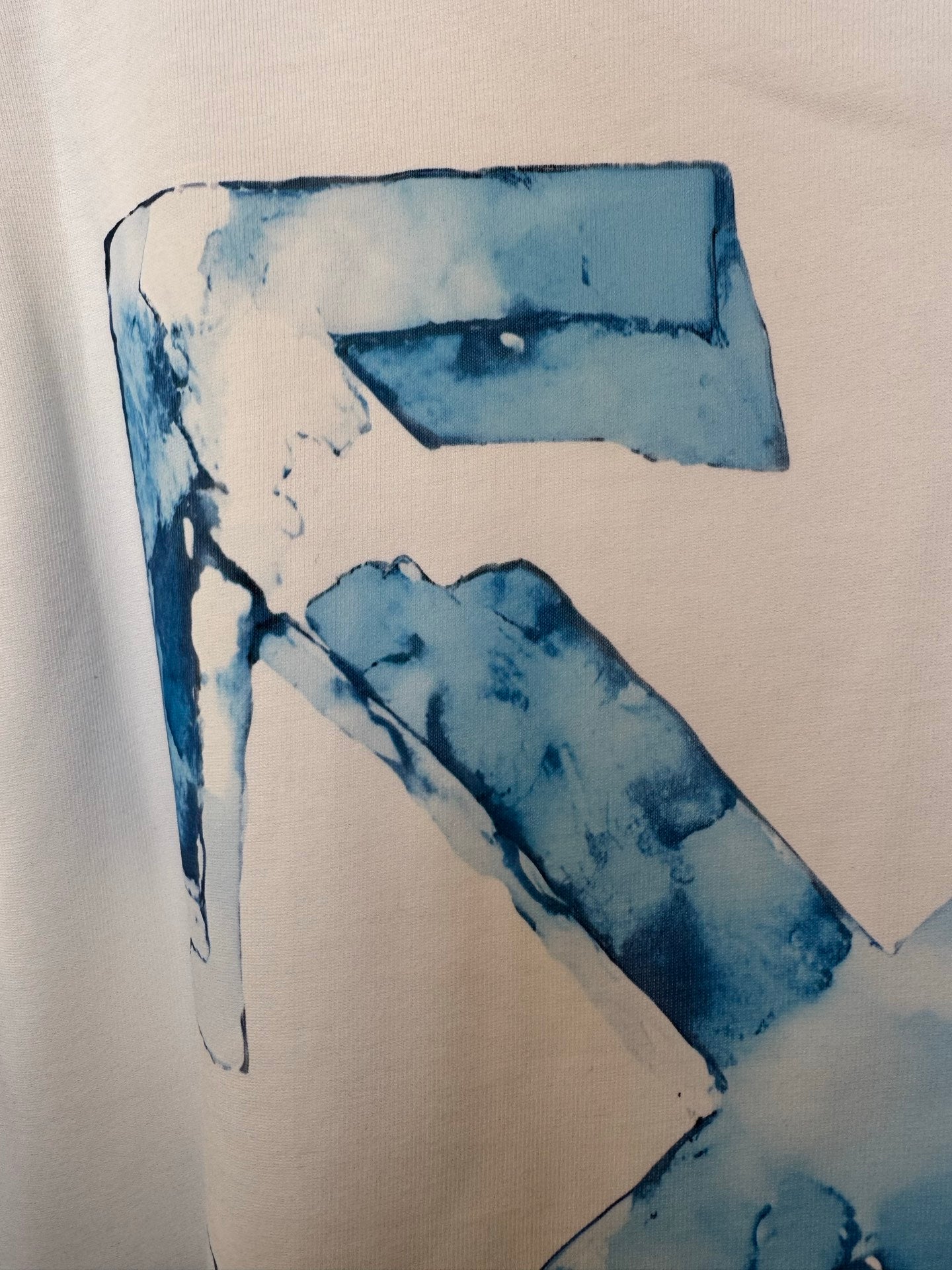 Off-white T-shirt close-up of blue letter 'X' print