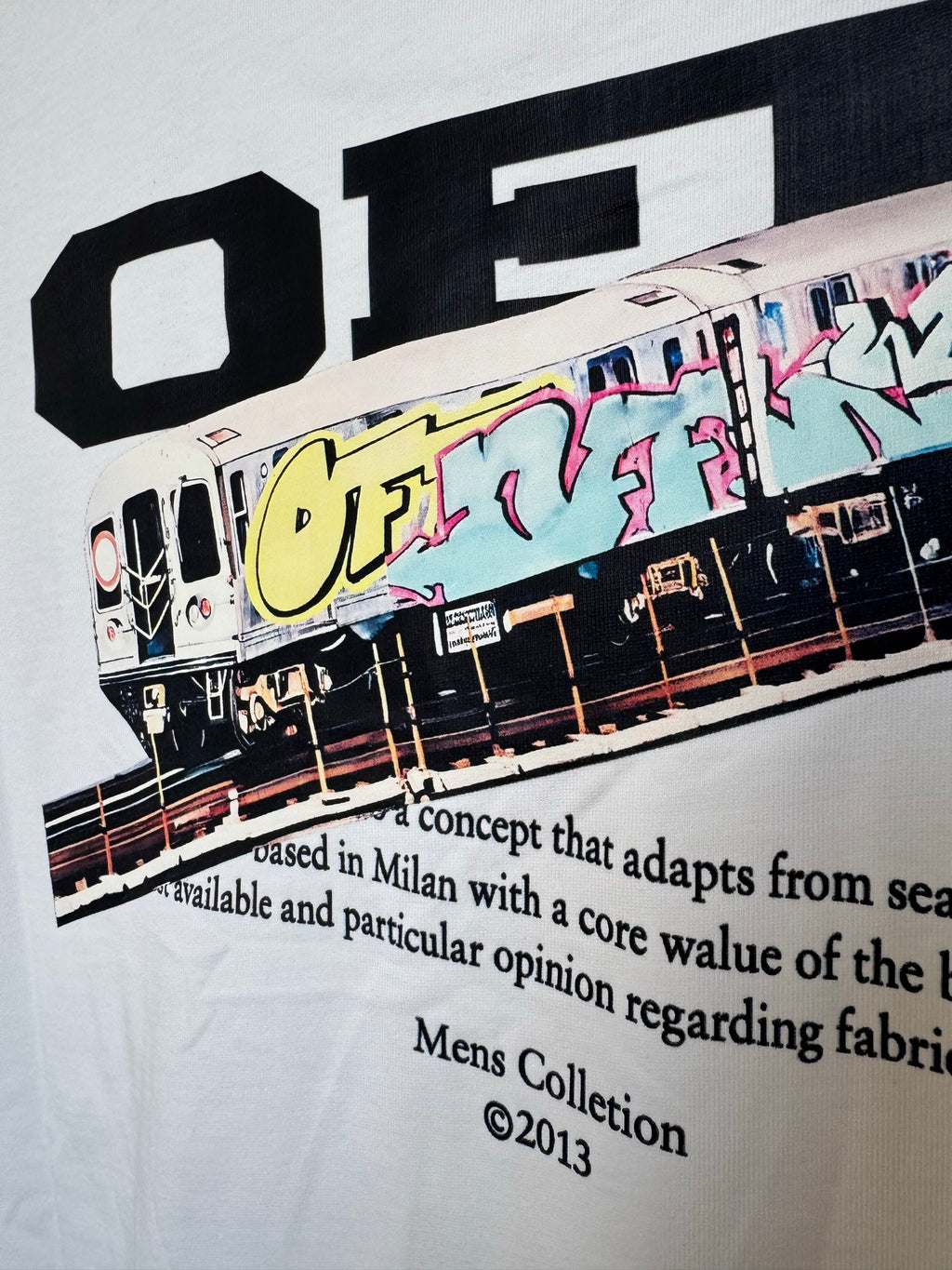 Off White T-shirt close-up of front train graphic and black headline text