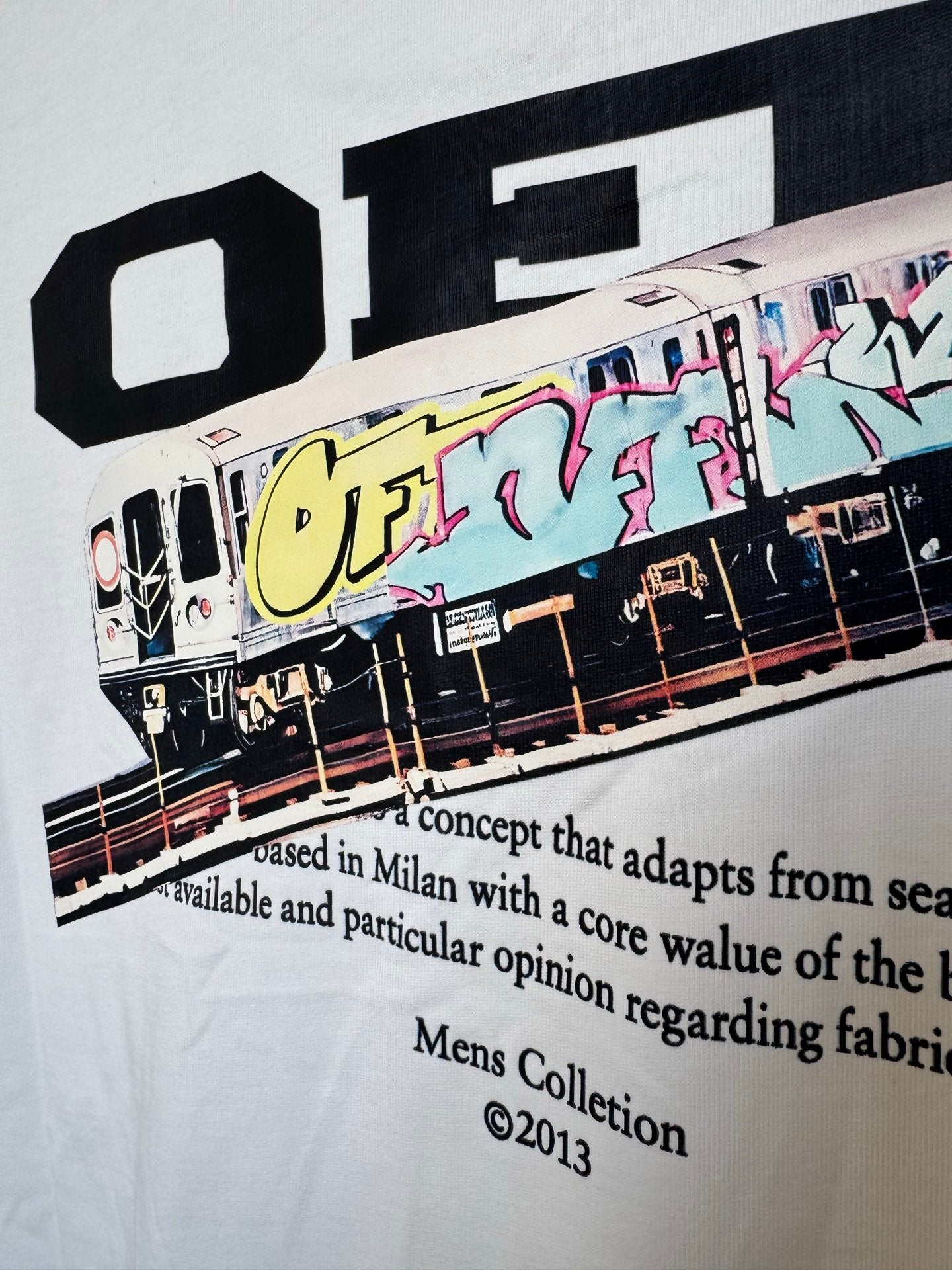Off White T-shirt close-up of front train graphic and black headline text