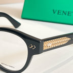 Eyeglasses close-up: black frame with gold patterned temple and gold hinge