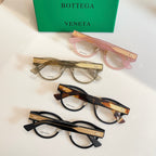 Assorted eyeglasses with pink and dark frames, featuring gold patterned temples