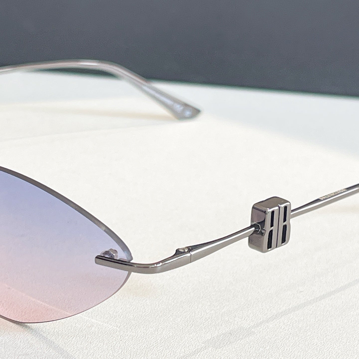 Balenciaga sunglasses close-up: silver temple arm with logo detail and clear lenses