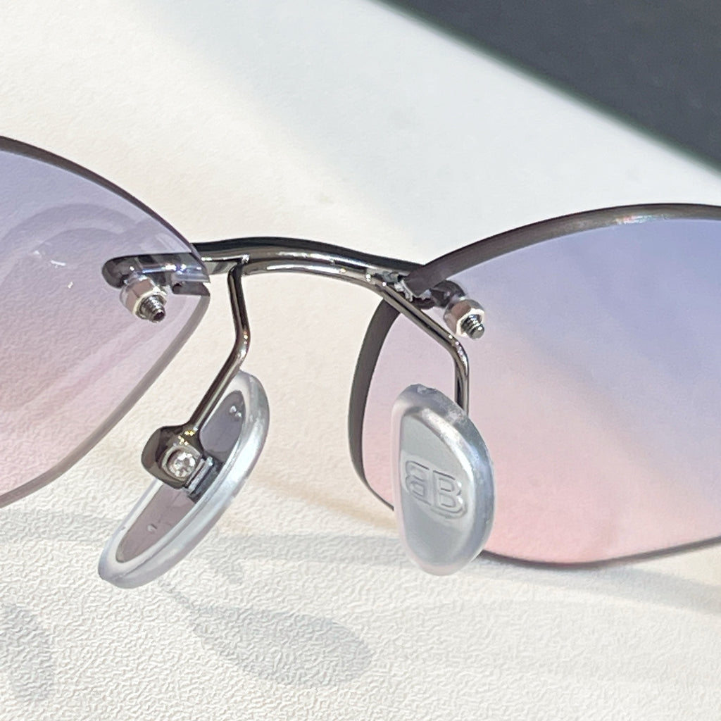 Balenciaga sunglasses close-up: silver frame with light purple-tinted lenses