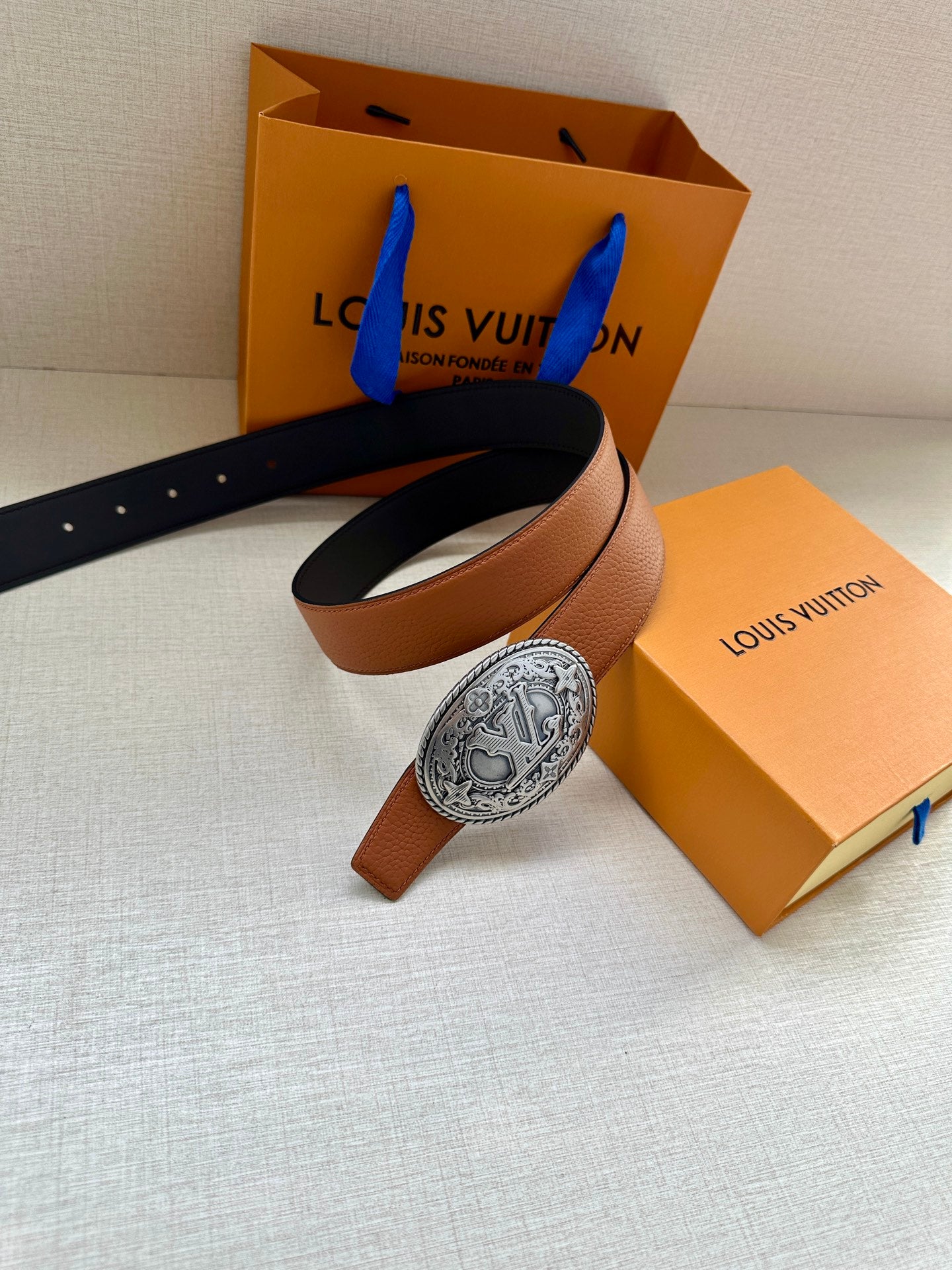 Louis Vuitton belt with tan and black straps and silver oval logo buckle