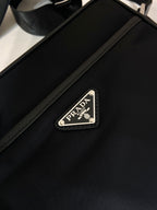 Leather strap with Prada logo patch and metal buckle on dark blue bag