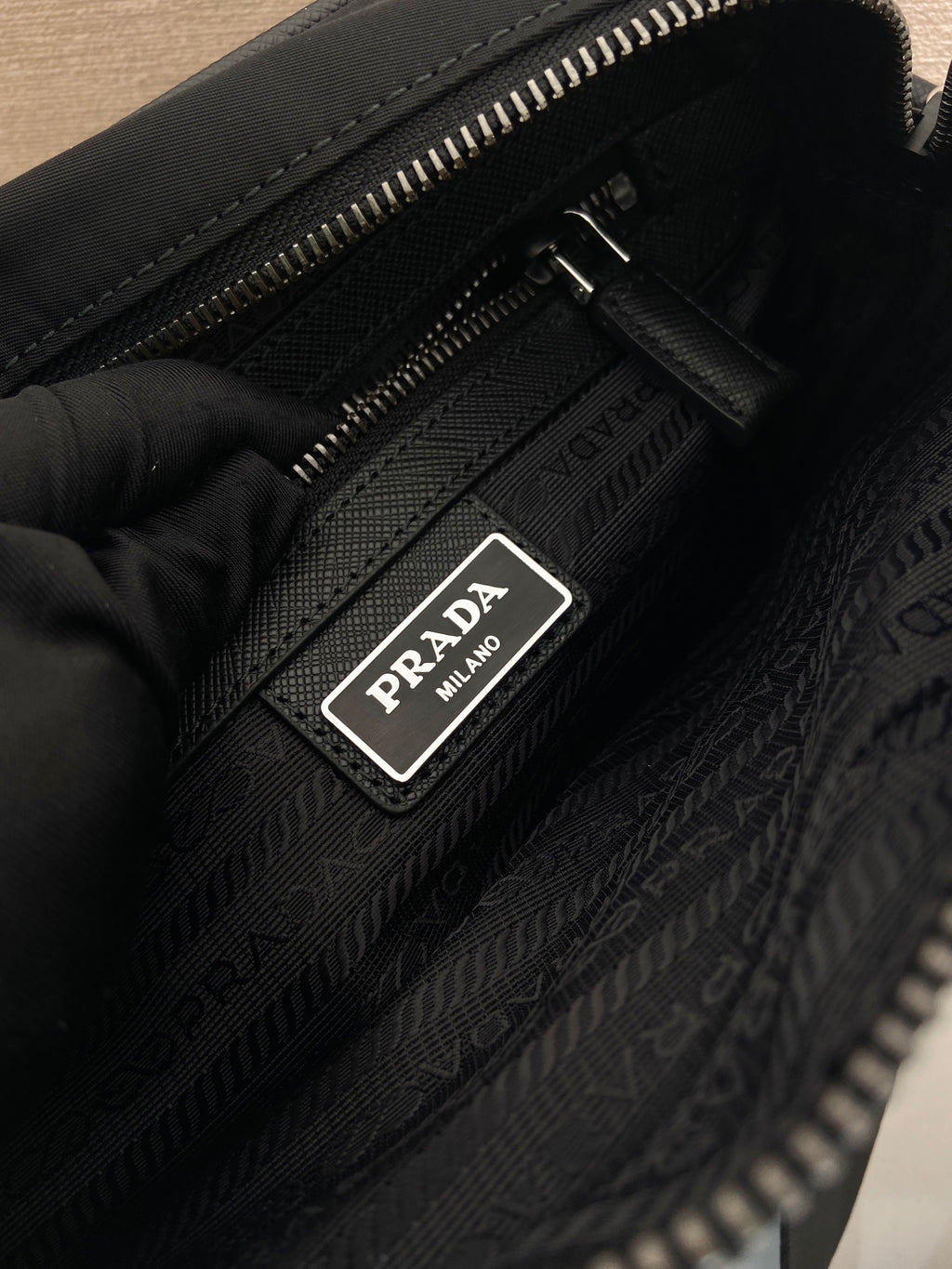 Black lining with Prada logo patch and zipper track inside the bag