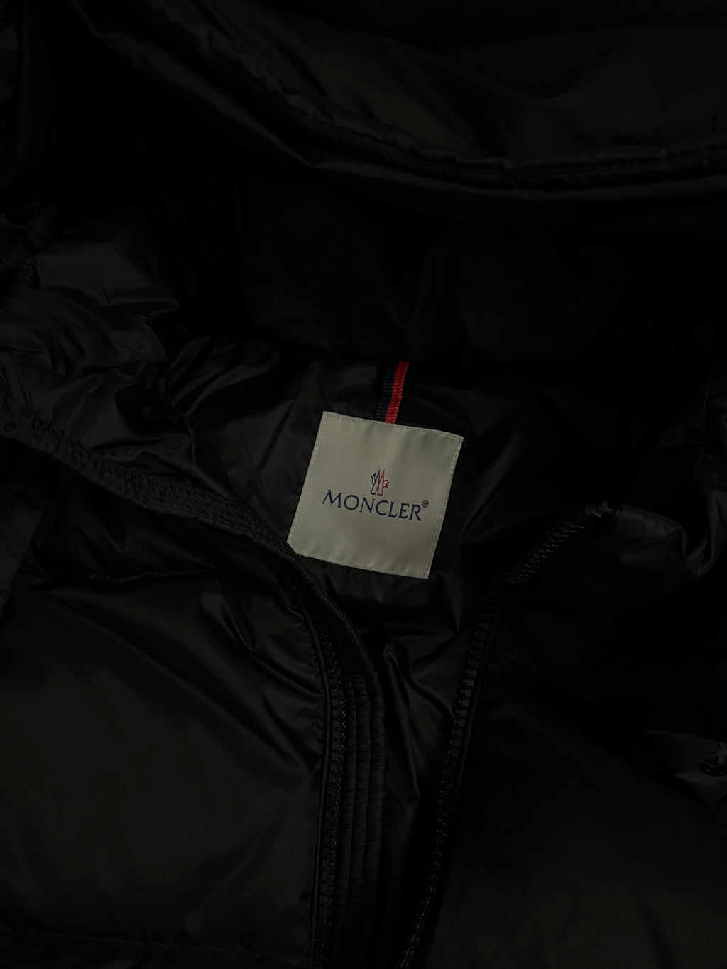 Moncler logo care tag on black puffer jacket lining