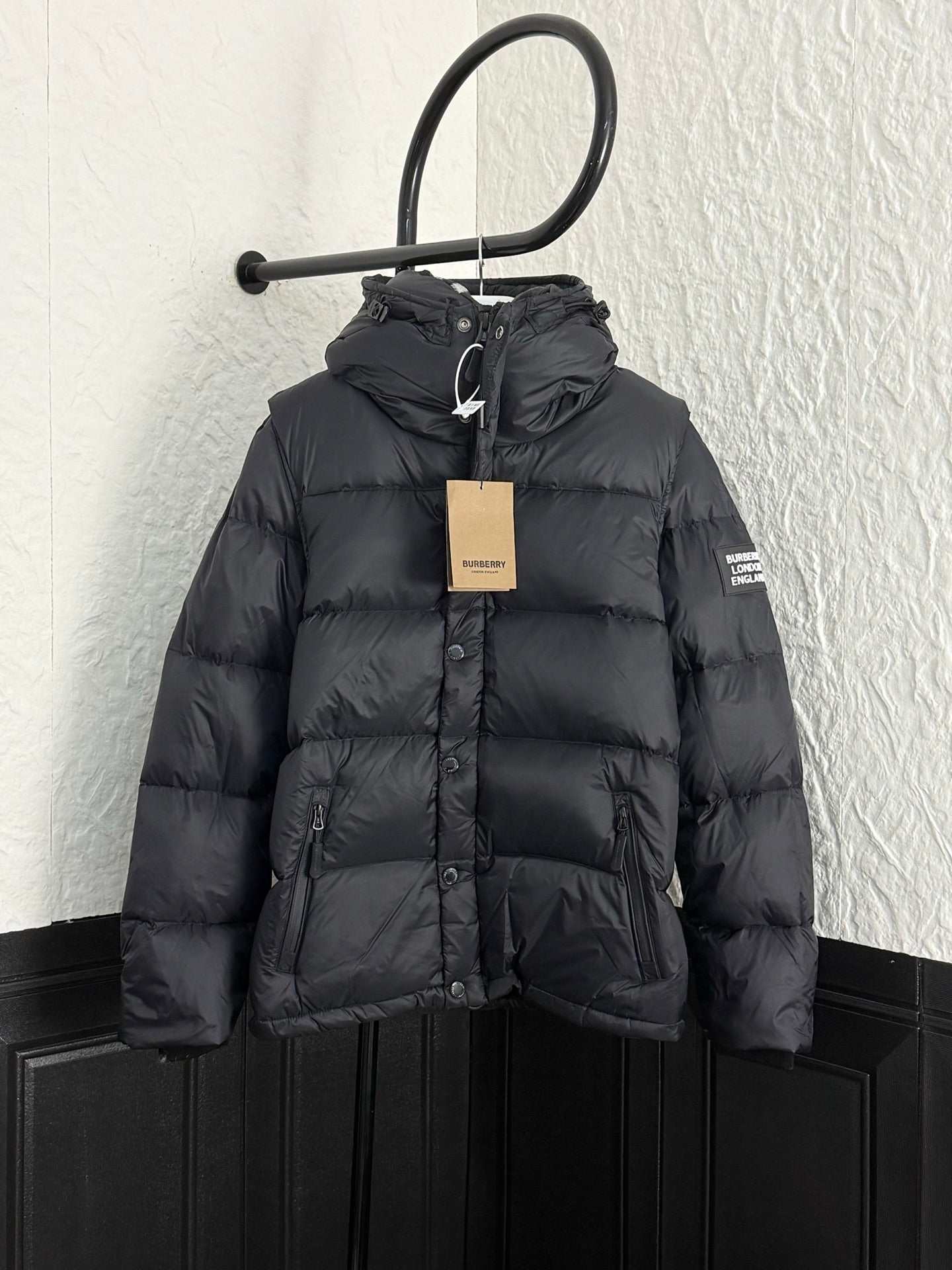 Long black puffer jacket with hood, front buttons, and drawcord collar