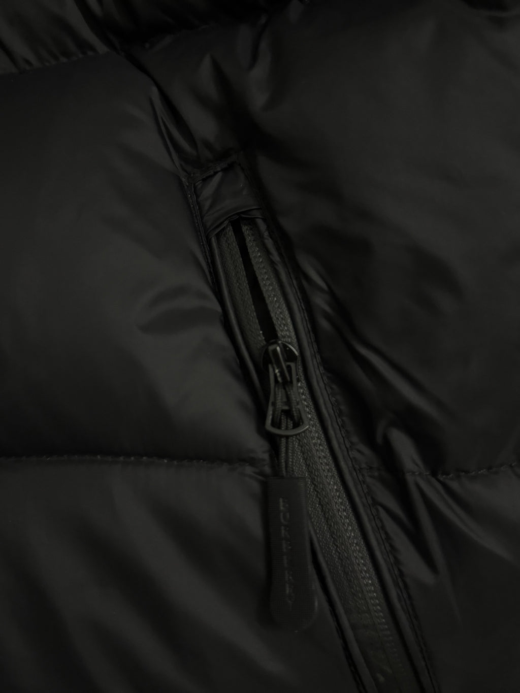 Black puffer jacket with visible zipper track and side seam detail