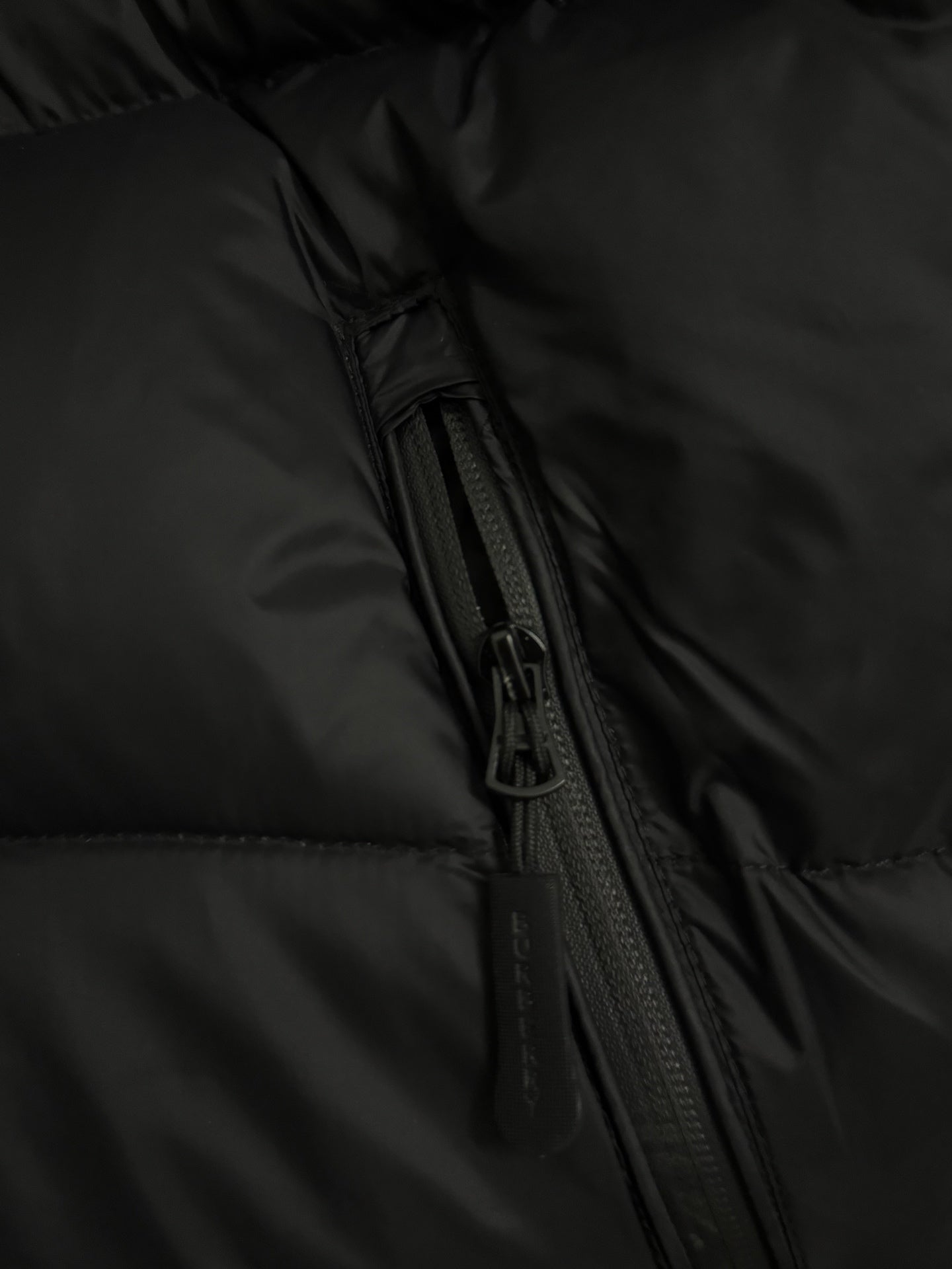 Black puffer jacket with visible zipper track and side seam detail