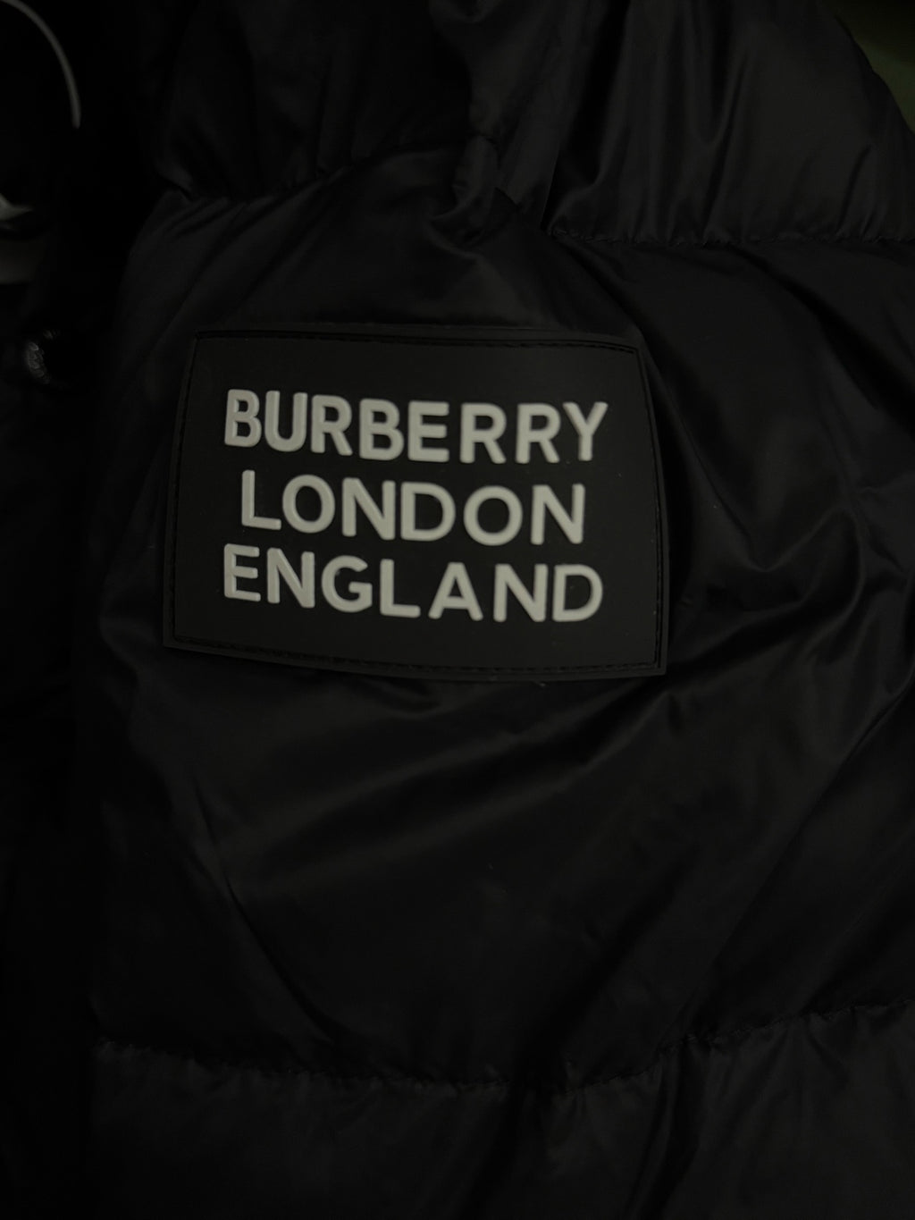 Black puffer jacket with “BURBERRY LONDON ENGLAND” label patch