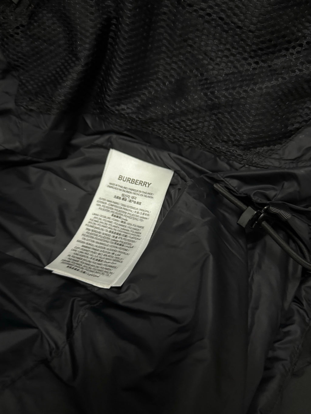 Black puffer jacket care label card attached inside lining