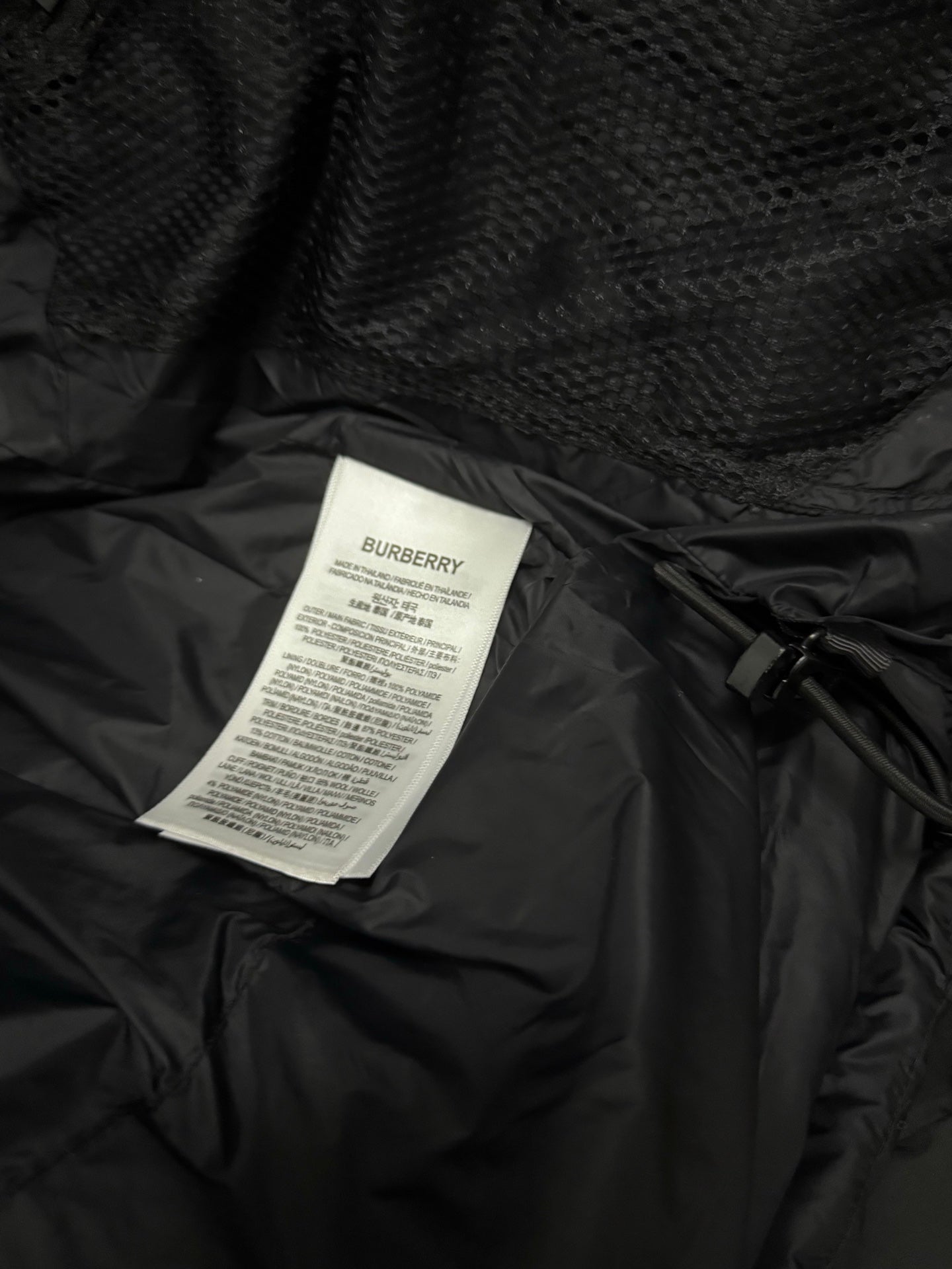 Black puffer jacket care label card attached inside lining
