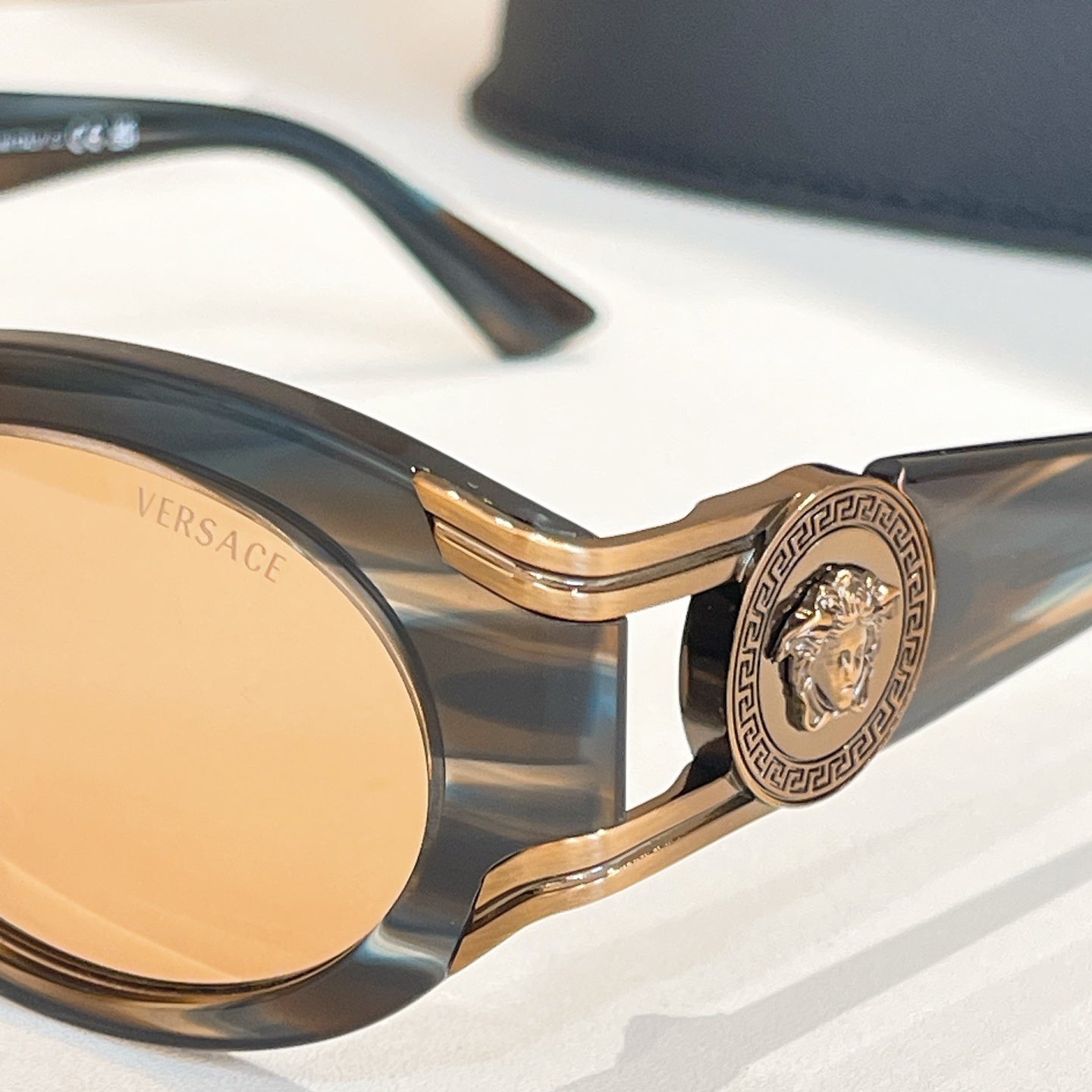 Versace sunglasses close-up with gold crest detail on tortoiseshell bridge