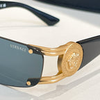 Gold-frame sunglasses close-up with dark blue lenses and engraved medallion