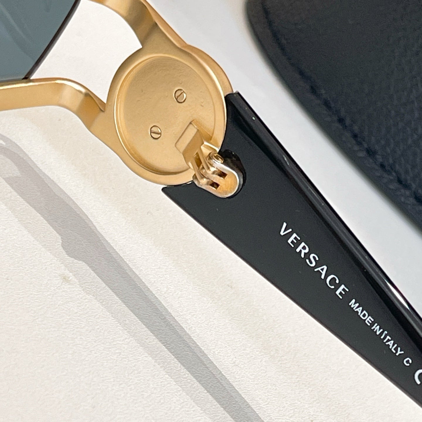 Gold temple hinge with engraved detail on sunglasses with dark arms