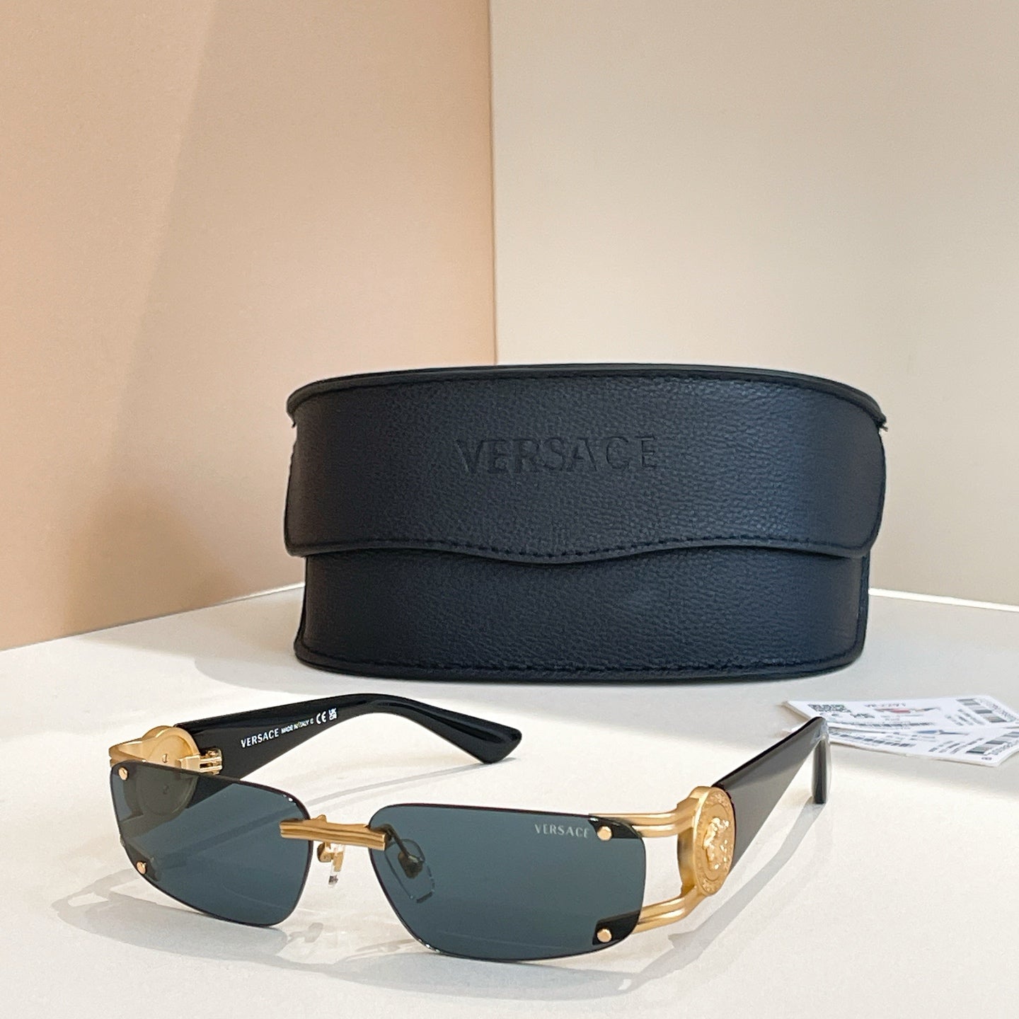 Blue-lens sunglasses with gold frame and black case behind