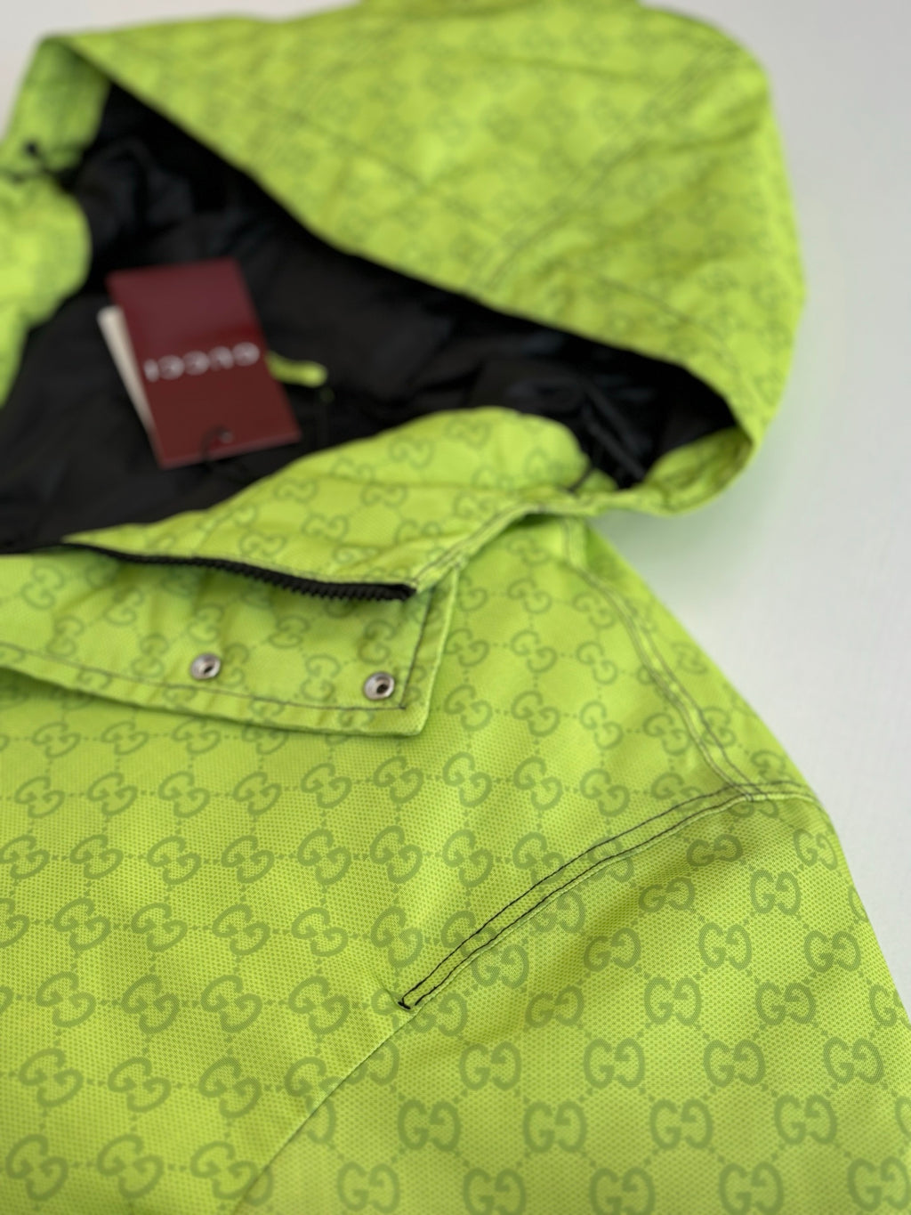 Lime green hooded puffer jacket with GG print, red Gucci tag and zipper