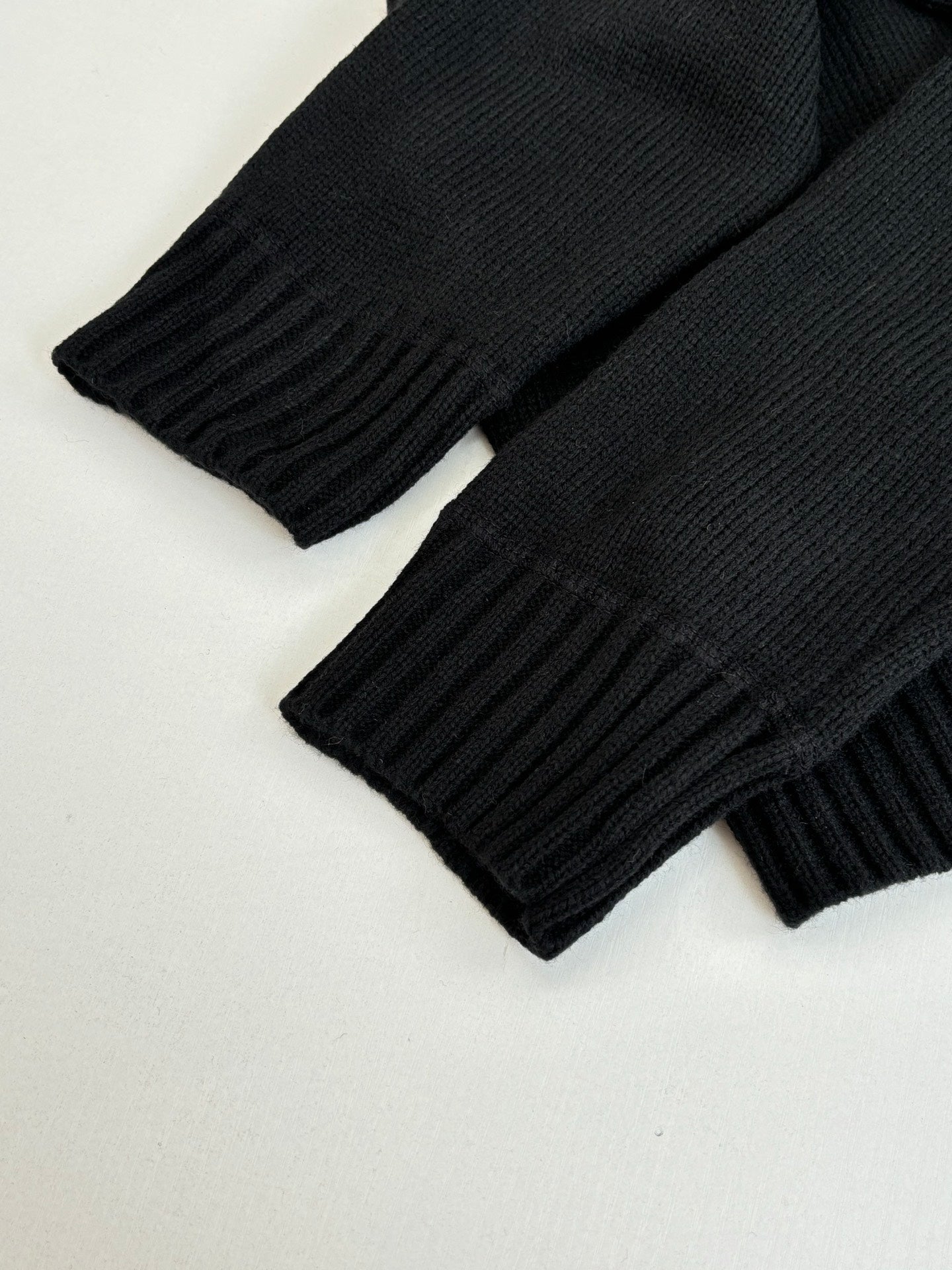 Black rib-knit sweater cuffs and sleeves with vertical rib texture
