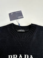 Black crewneck sweater neckline with neck tag and partial PRADA lettering
