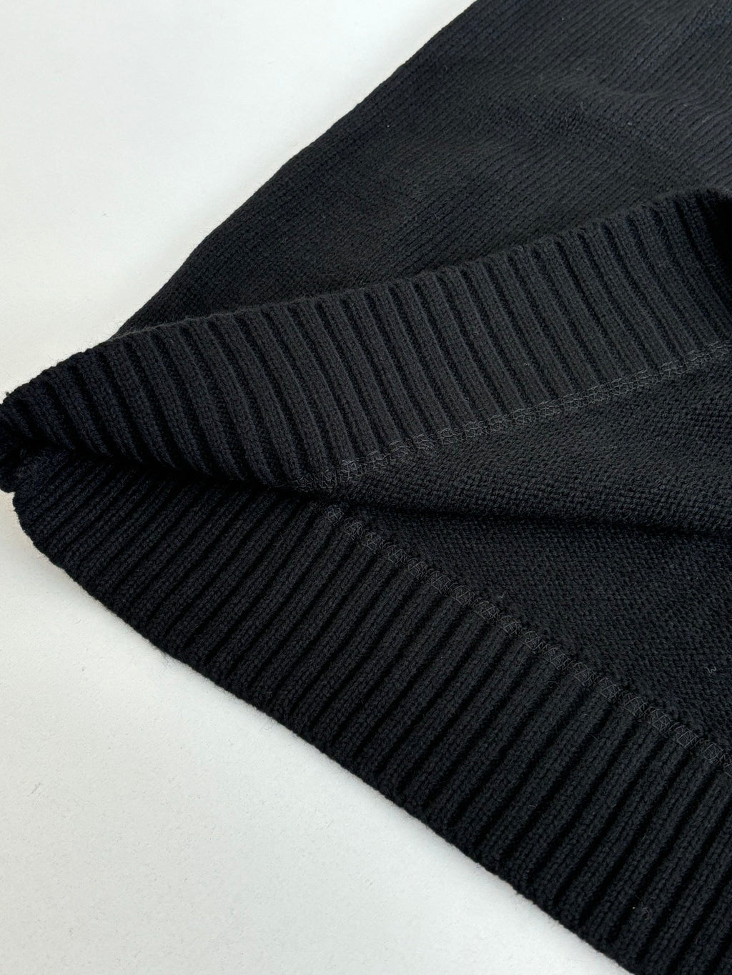 Black sweater fabric fold with ribbed knit trim detail at the edge