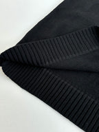 Black sweater fabric fold with ribbed knit trim detail at the edge