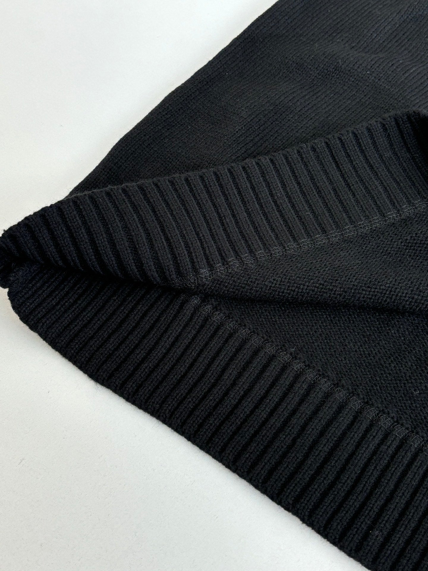 Black sweater fabric fold with ribbed knit trim detail at the edge
